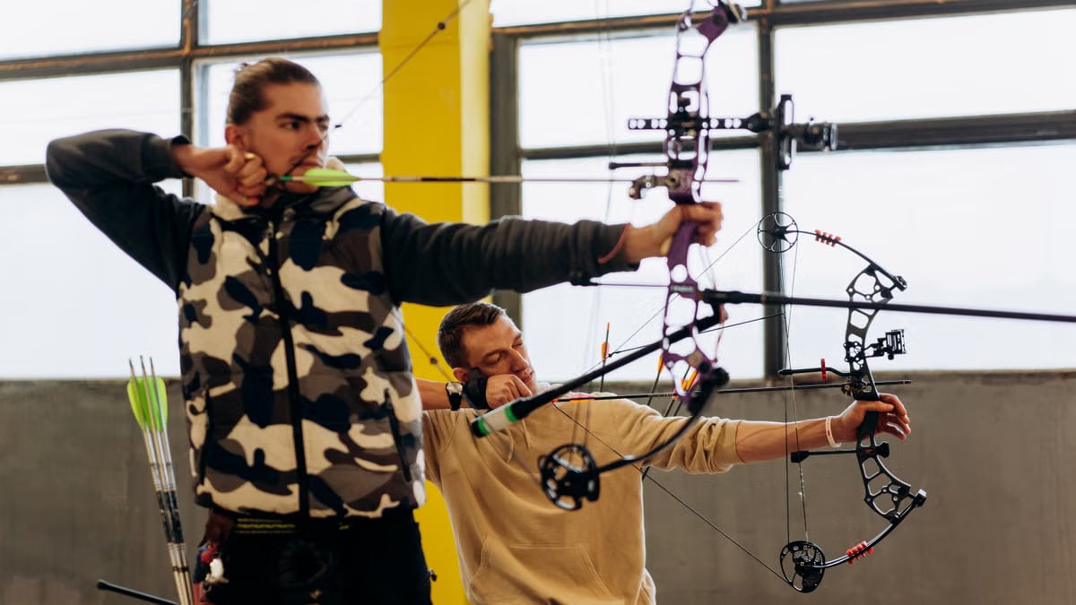 Two archers concentrate intensely during an indoor archery competition, showcasing skill and determination.